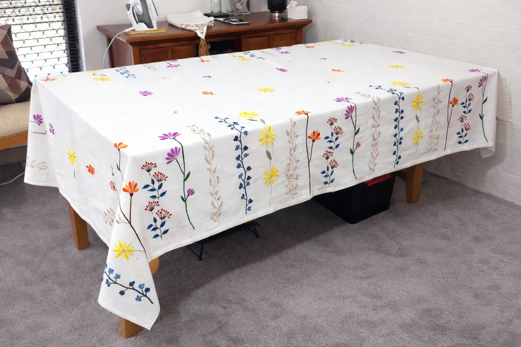 hand embroidered floral rectangle tablecloth on white linen cloth.