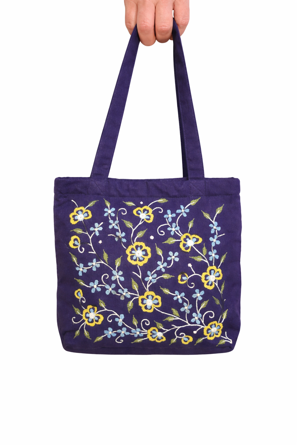 Dark blue tote with hand embroidered flowers. Zip close and internal zip close pocket. Flowers are in sunshine and pale blue with green leaves. Made in India by women's fair trade collective.